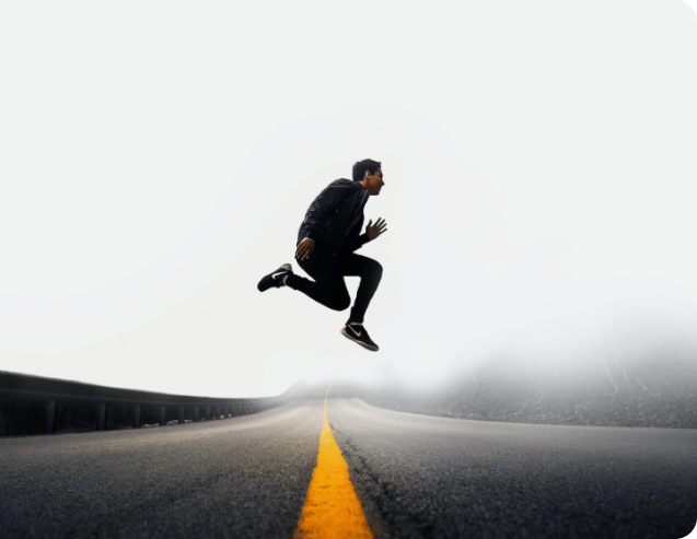 image of a man in the middle of a jump from the center of an asphalt road against a gray sky